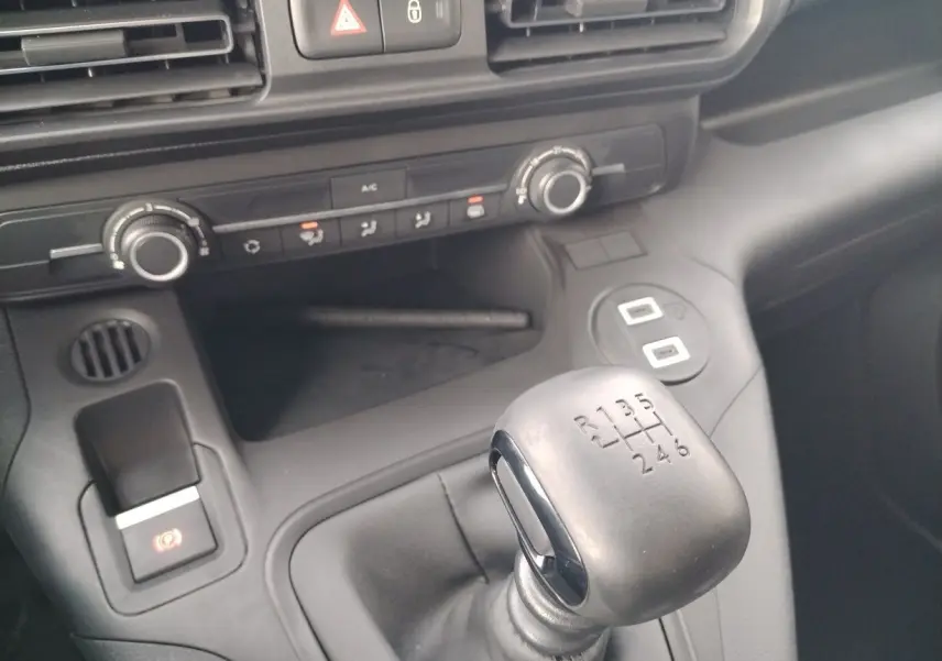 Gros plan sur le levier de vitesses manuel noir et la console centrale grise du Peugeot Partner Fourgon blanc Icy 2025.
