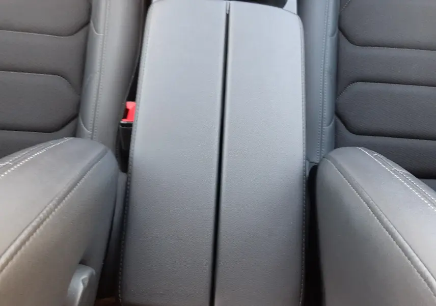 Vue plongeante sur l'accoudoir central noir et les sièges avant en cuir gris du Citroën C5 Aircross 2024.