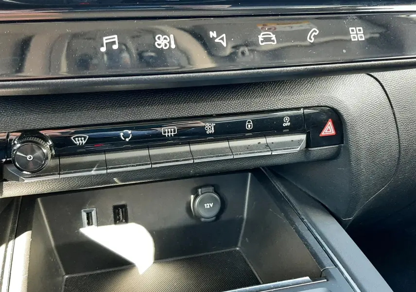 Vue rapprochée de la console centrale noire du Citroën C5 Aircross 2024, avec commandes tactiles et prise 12V visible.
