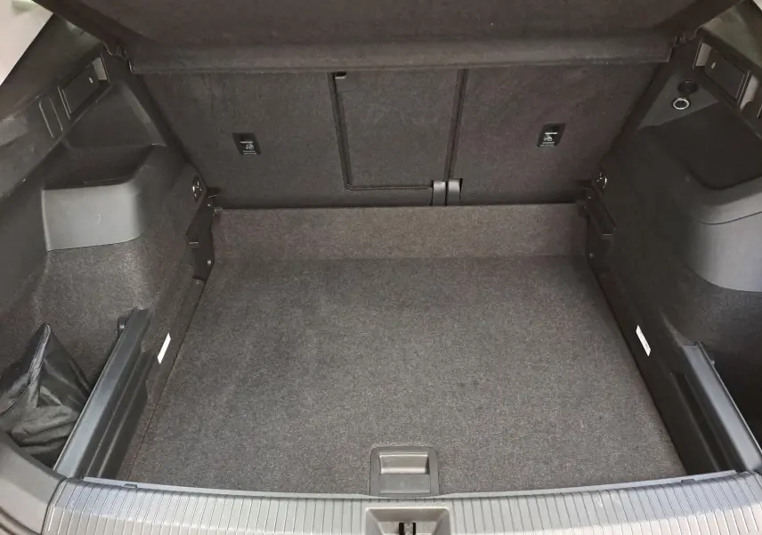 Vue intérieure du coffre spacieux et propre du Volkswagen Tiguan 2025, avec revêtement gris foncé uniforme.