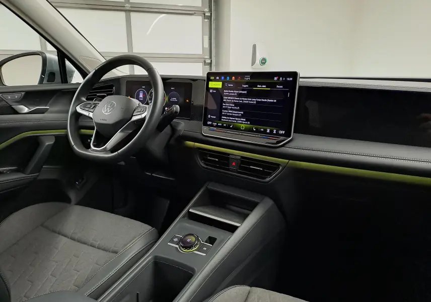 Vue intérieure côté conducteur du Volkswagen Tiguan 2025, avec tableau de bord noir et écran tactile central lumineux.