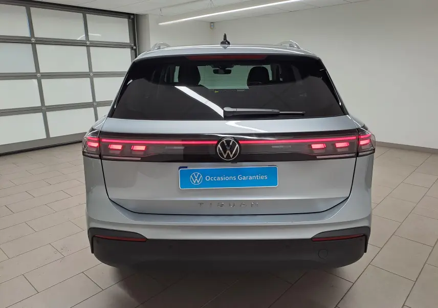 Vue arrière du Volkswagen Tiguan 2025 en Argent Dolomite avec feux arrière allumés et logo VW central.