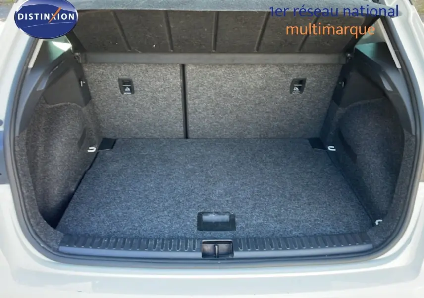 Coffre ouvert vu de l'arrière d'un SEAT Arona blanc avec toit gris, montrant l'espace de chargement vide et doublé de moquette grise.