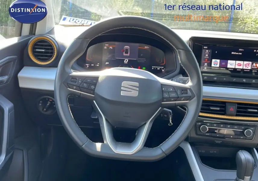 Vue intérieure centrée sur le volant cuir et tableau de bord numérique du SEAT Arona blanc toit gris 2025.