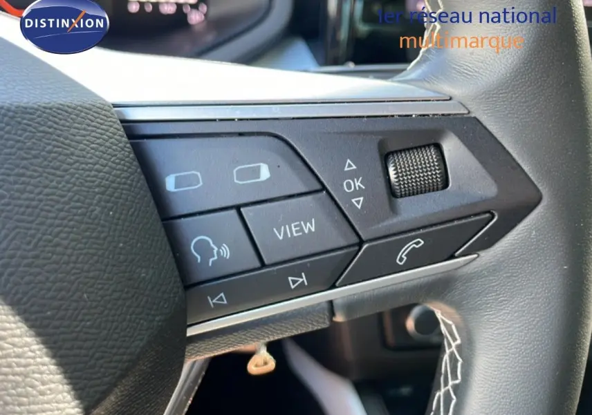 Gros plan sur les commandes gauche du volant cuir noir du SEAT Arona 2025, boutons multifonctions et molette visibles.