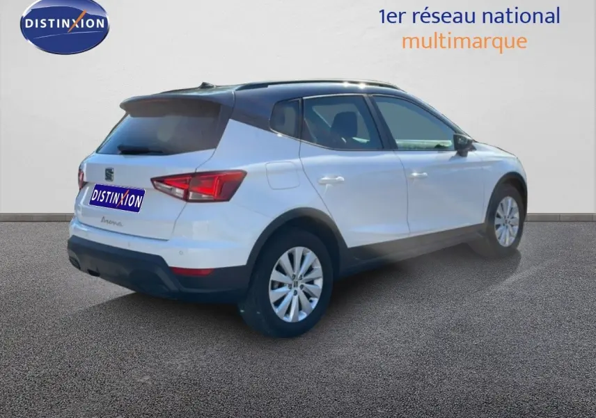 Vue 3/4 arrière droite d'un SEAT Arona blanc avec toit gris, jantes alliage et détails noirs sur les bas de caisse.