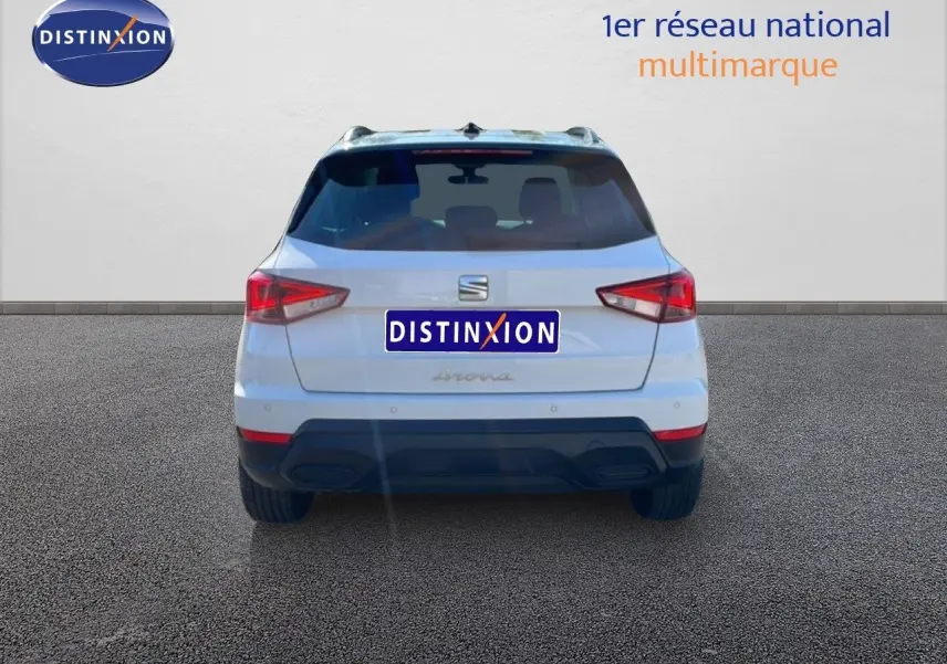 Vue arrière d'un SEAT Arona blanc avec toit gris, mettant en valeur ses feux arrière anguleux et son pare-chocs noir.
