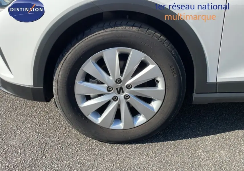 Gros plan sur la roue avant gauche du SEAT Arona blanc avec jante argentée et toit gris visible en partie.