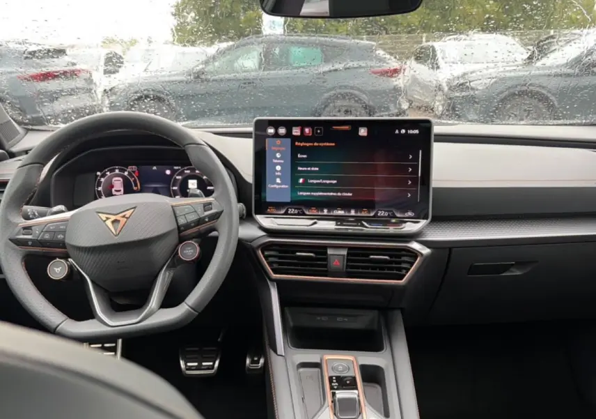 Vue intérieure du tableau de bord et volant multifonction du CUPRA Formentor 1.5 etsi hybrid 2026, avec écran tactile et pluie sur le pare-brise.