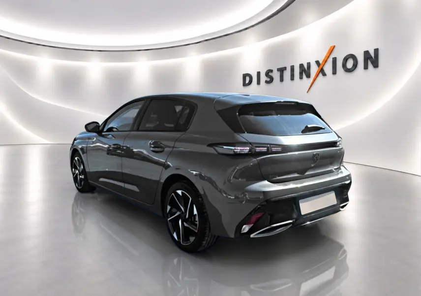 Peugeot 308 gris 3/4 arrière droit dans un showroom lumineux avec jantes alu et feux LED distinctifs.