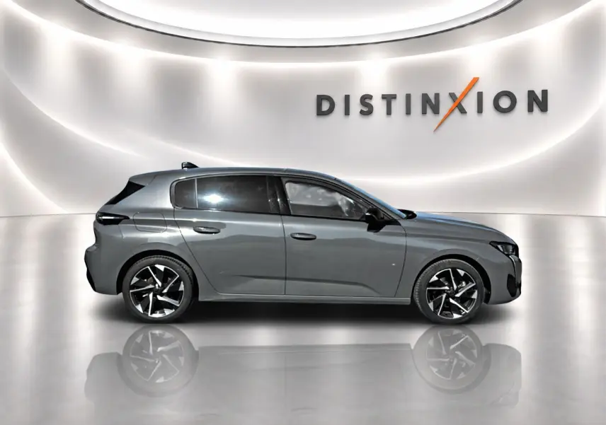 Peugeot 308 gris vue de profil côté gauche, jantes alliage noires et vitres arrière surteintées dans un studio lumineux.
