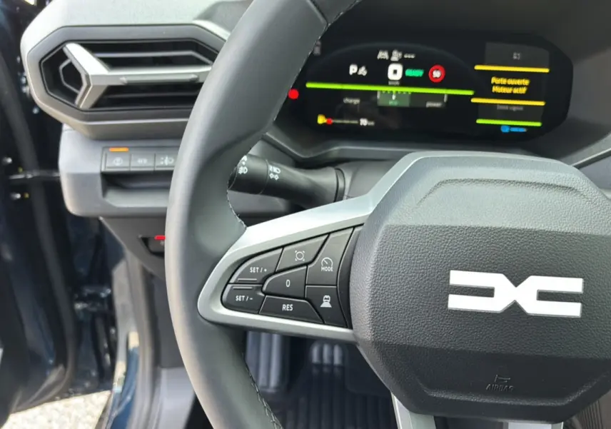 Gros plan sur le volant cuir et tableau de bord digital du Dacia Bigster Hybrid 155 bleu indigo avec portes ouvertes.