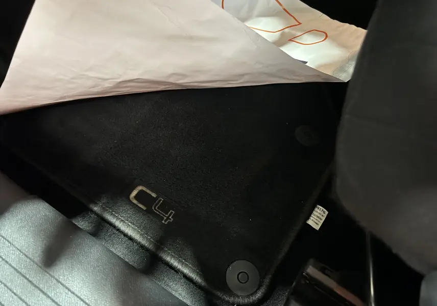 Tapis de sol noir avec logo C4 visible sous le siège avant d'une Citroën C4 orange PureTech 2021.