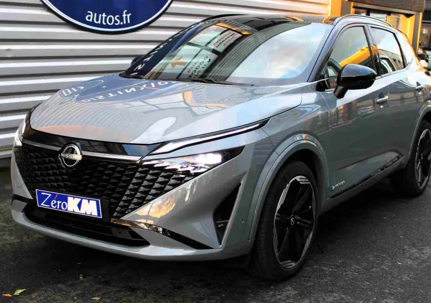 Nissan Qashqai 2025 gris céramique avec toit noir, vue 3/4 avant mettant en valeur sa calandre distinctive et ses jantes noires.