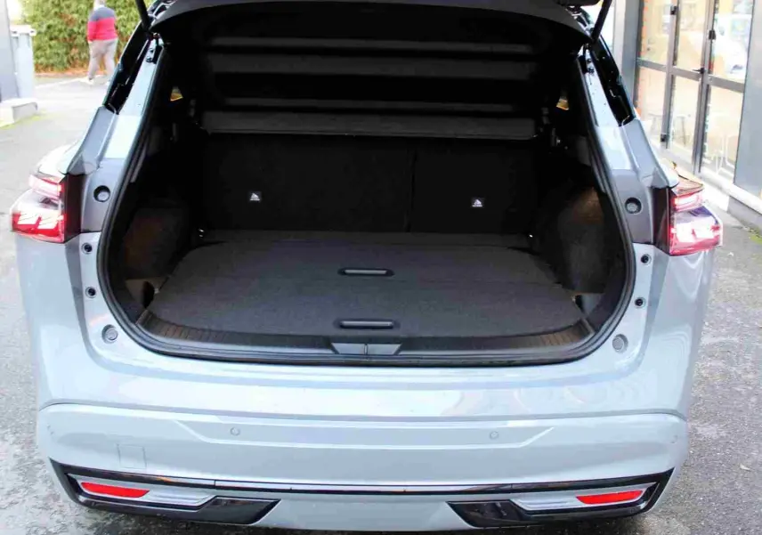 Vue intérieure centrée sur le volant Nissan du Qashqai 2025 avec tableau de bord numérique et écran tactile de navigation.