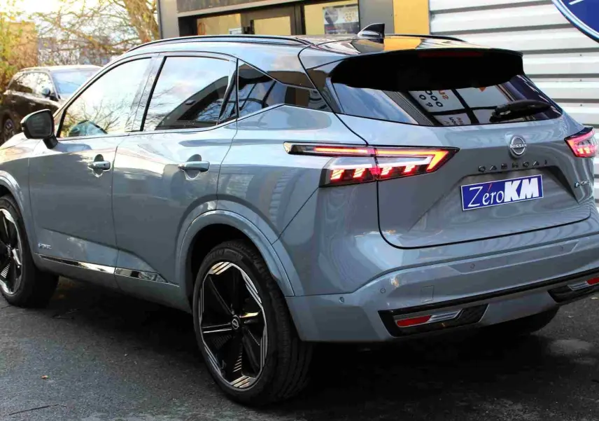 Vue avant du Nissan Qashqai 2025 gris céramique avec toit noir, mettant en valeur sa calandre noire et ses phares LED fins.
