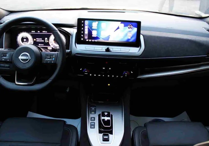 Nissan Qashqai 2025 gris céramique avec toit noir, vue 3/4 avant mettant en valeur sa calandre distinctive et ses jantes stylées.