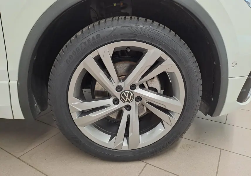Gros plan sur la roue avant droite du Volkswagen Tiguan Allspace blanc pur, jante alliage R-Line à design moderne.