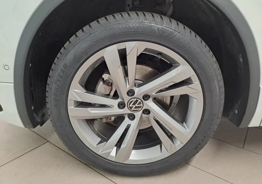 Gros plan sur la roue avant droite du Volkswagen Tiguan Allspace blanc pur 2023 avec jante alliage R-Line et pneu Goodyear.