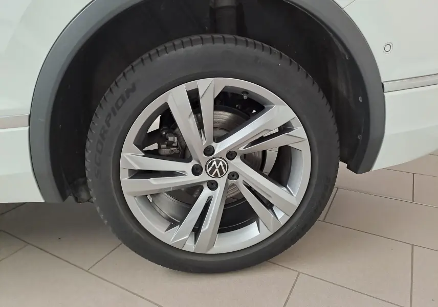 Gros plan sur la roue avant droite du Volkswagen Tiguan Allspace blanc pur 2023 avec jante alliage R-Line distinctive.