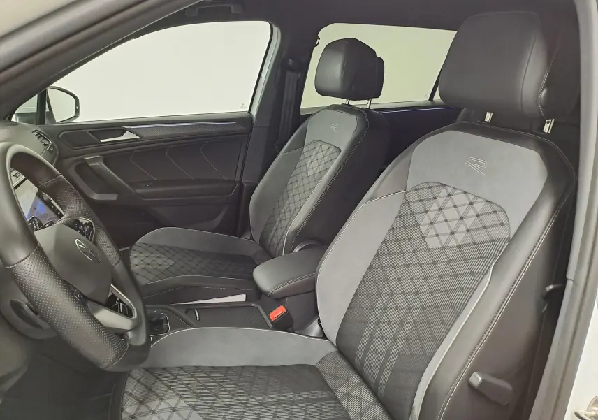 Vue intérieure côté conducteur du Volkswagen Tiguan Allspace blanc pur 2023, sièges R-Line en tissu et alcantara gris avec surpiqûres.