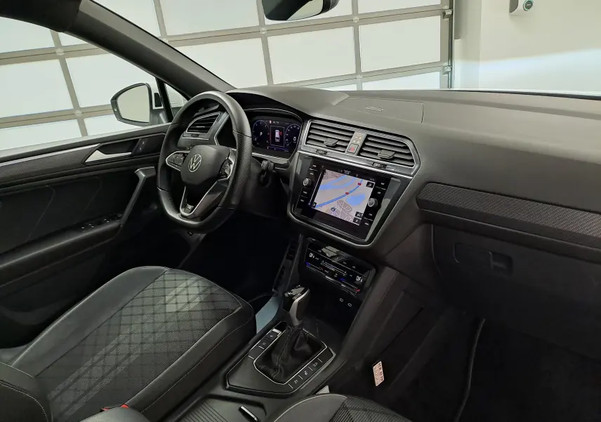 Intérieur du Volkswagen Tiguan Allspace 2023, vue côté conducteur, tableau de bord noir avec écran tactile et volant multifonction.