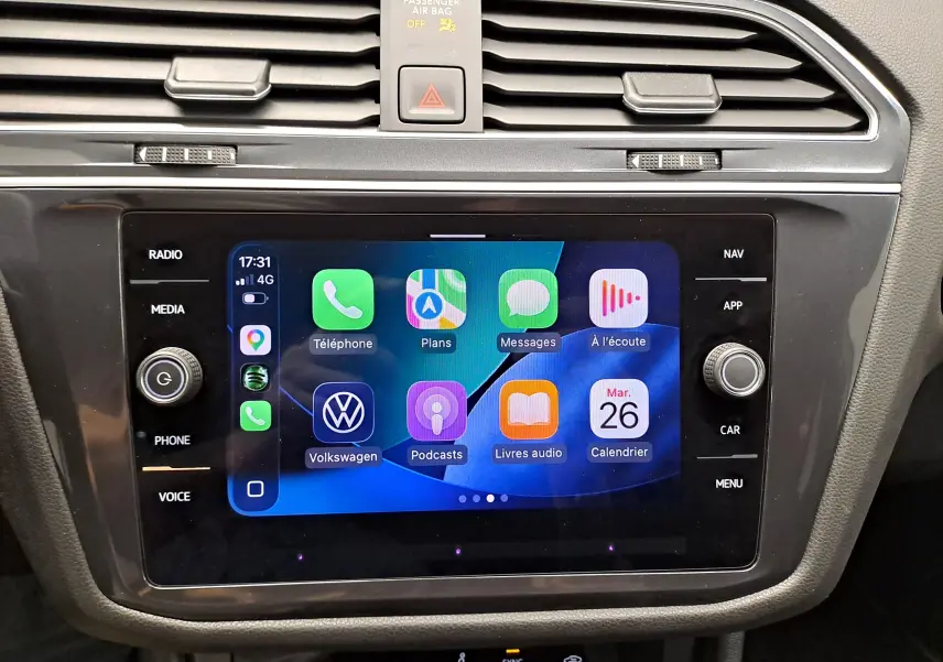 Vue rapprochée de l’écran tactile central du Volkswagen Tiguan Allspace blanc, affichant l’interface Apple CarPlay.