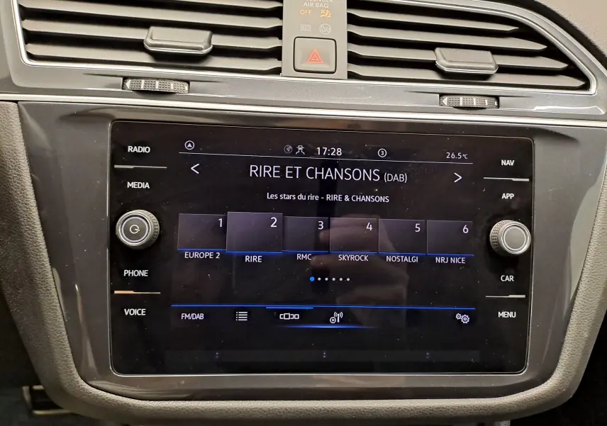 Gros plan sur l'écran tactile central du Volkswagen Tiguan Allspace 2023, affichant les stations radio en mode DAB.