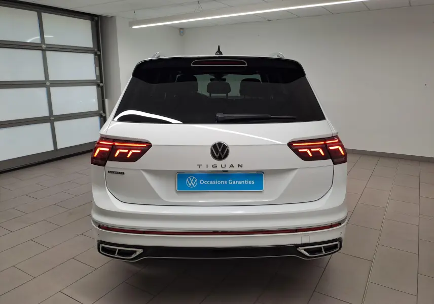 Vue arrière d’un Volkswagen Tiguan Allspace blanc pur 2023 avec feux LED allumés et finition R-Line visible.