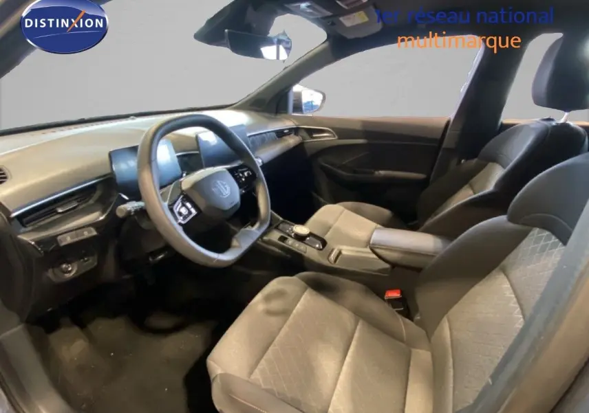 Intérieur de la MG3 1.5 Hybrid 2024 vu côté conducteur, sièges tissu gris noir et tableau de bord moderne.