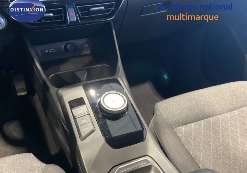 Vue rapprochée de la console centrale de la MG3 1.5 Hybrid 195ch Comfort 2024 avec molette de boîte auto et sièges tissu gris.