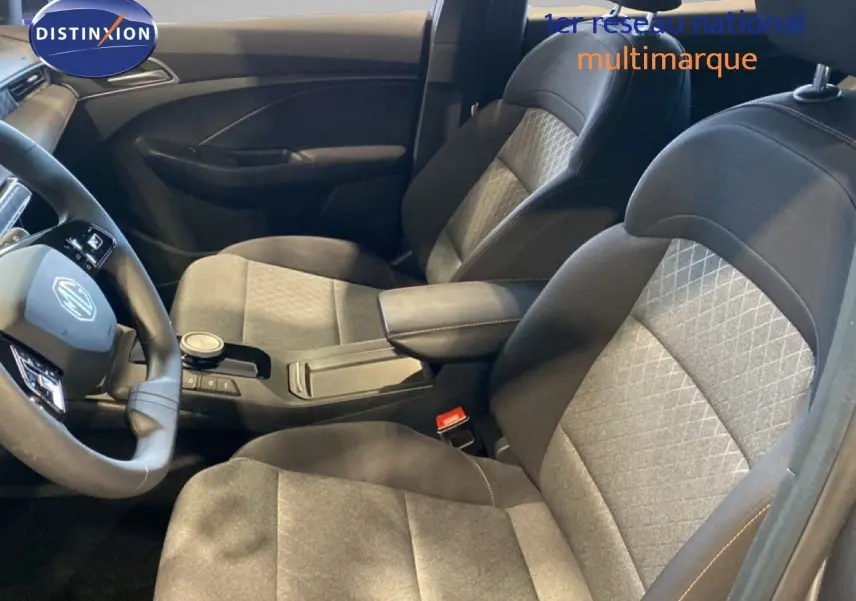 Vue intérieure côté conducteur de la MG3 1.5 Hybrid 2024 avec sièges tissu gris et noir et console centrale moderne.