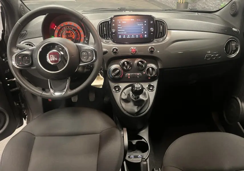 Intérieur avant de la Fiat 500 gris, tableau de bord avec écran tactile et volant noir en éco-cuir.