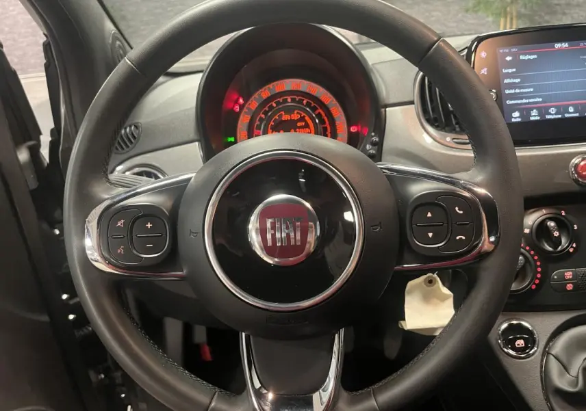 Vue rapprochée du volant noir en éco-cuir de la Fiat 500 gris, avec tableau de bord et commandes visibles.