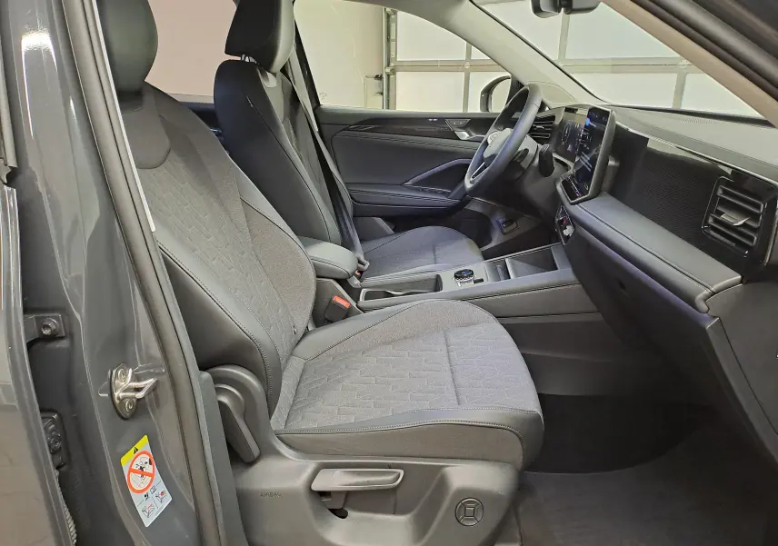 Intérieur avant droit du Volkswagen Tiguan 2024 gris Urano, sièges tissu et tableau de bord moderne avec écran tactile.