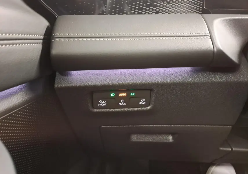 Gros plan sur le panneau de commandes des feux avec éclairage ambiant violet dans l'habitacle gris du Volkswagen Tiguan 2024.