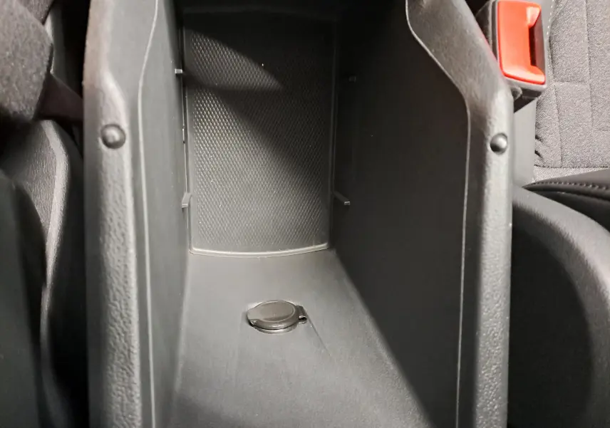 Gros plan sur le rangement central intérieur noir du Volkswagen Tiguan 2024, avec bouton circulaire visible.