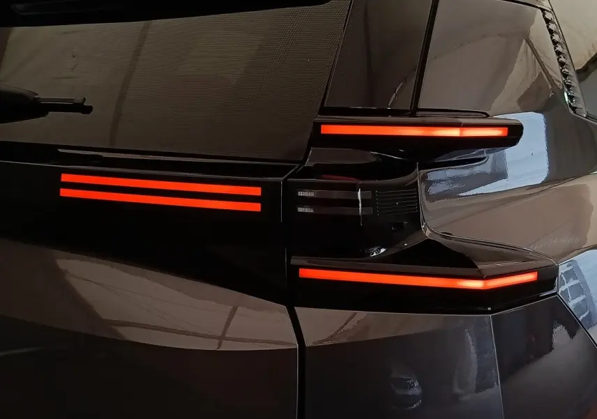Gros plan sur le feu arrière droit rouge lumineux d'une Citroën C5 hybride gris foncé 2025.