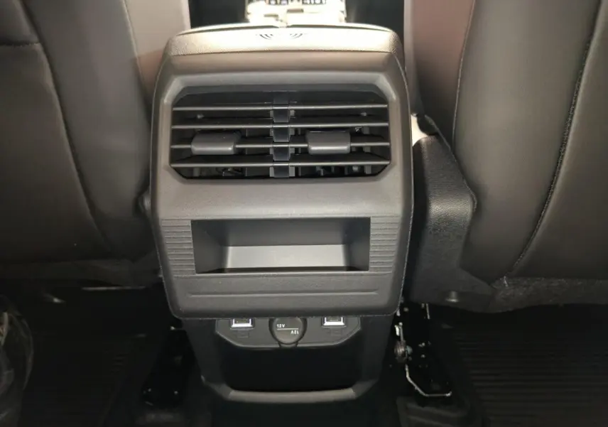 Vue rapprochée de la console centrale arrière noire du Citroën C5 Hybride 2025 avec bouches d’aération et prises USB.