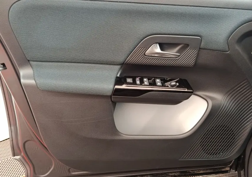 Détail de la porte côté conducteur de la Citroën C5 hybride 2025, avec commandes électriques et finition bicolore grise.