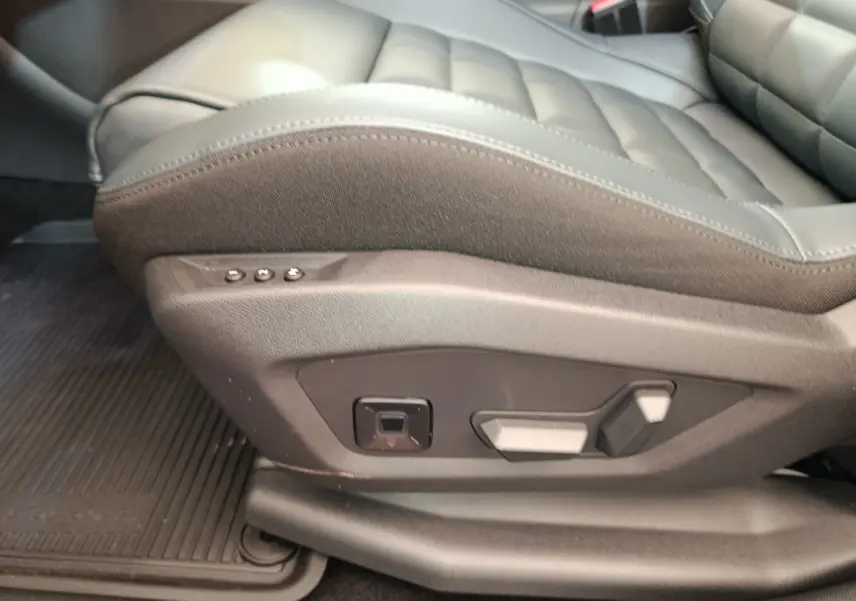 Gros plan sur le côté gauche du siège avant en cuir gris foncé avec commandes électriques sur une Citroën C5 hybride 2025.