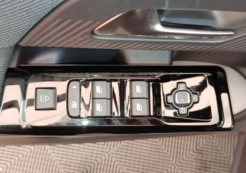 Gros plan sur la commande de lève-vitres et réglage des rétroviseurs côté conducteur d'une Citroën C5 hybride gris foncé.