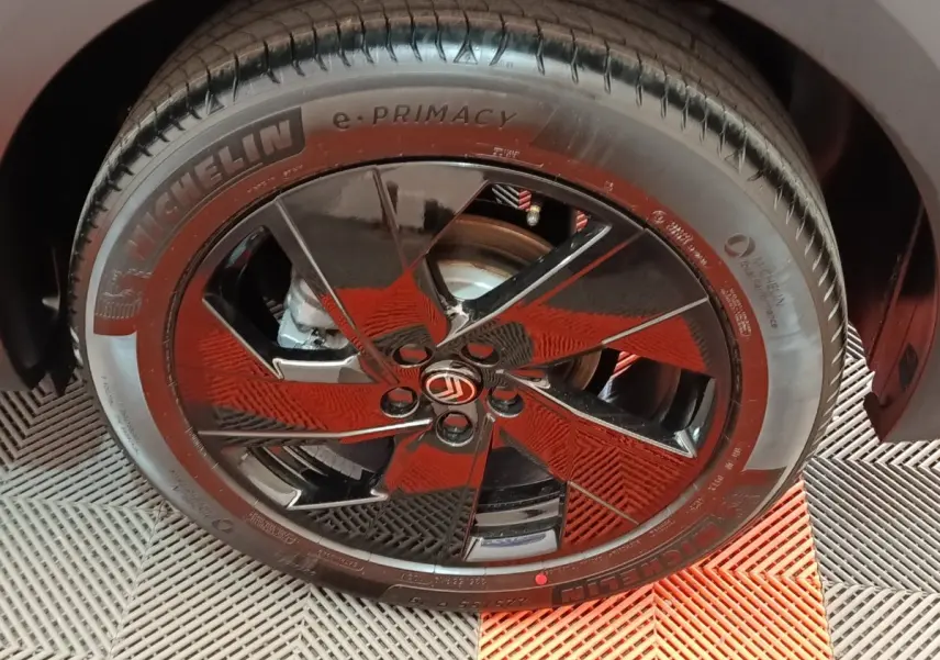 Gros plan sur la roue avant droite d'une Citroën C5 gris foncé avec jante noire brillante et logo Citroën central.