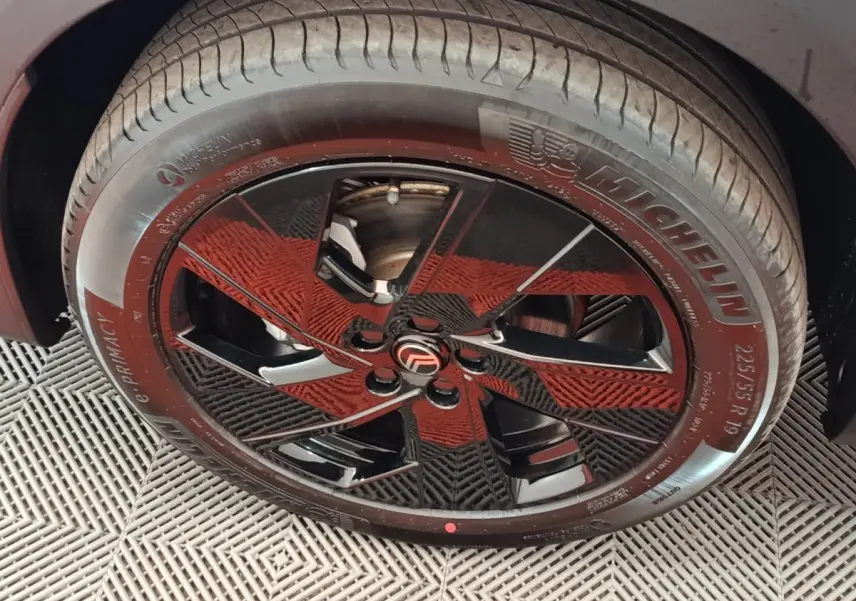 Gros plan sur la roue avant droite avec jante noire brillante et pneu Michelin sur Citroën C5 gris foncé.