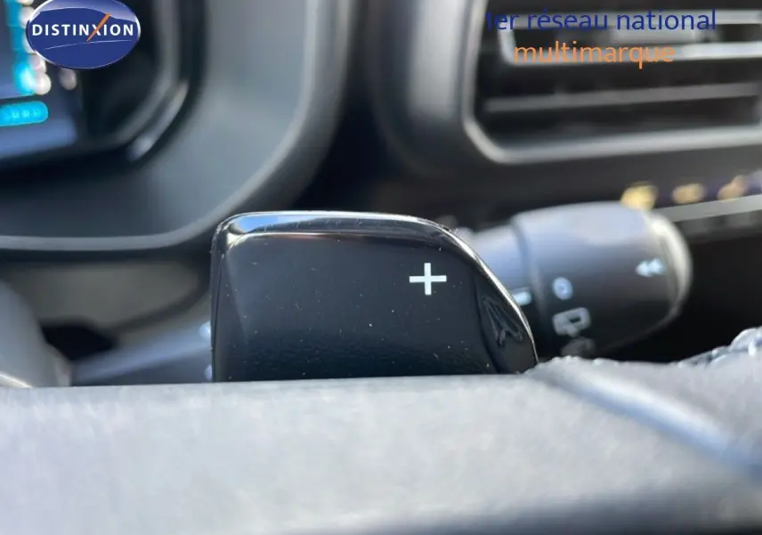 Gros plan sur la palette de changement de vitesse "+" côté droit du volant dans l'habitacle noir du Citroën Berlingo blanc glacier 2025.