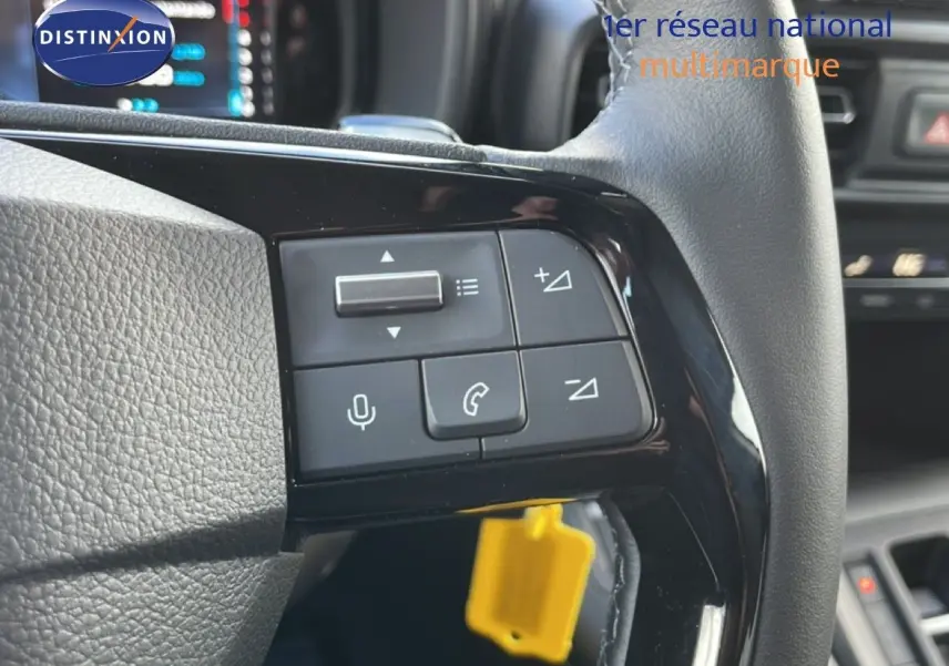 Gros plan sur les commandes au volant d’un Citroën Berlingo blanc glacier, avec boutons de volume et téléphone visibles.