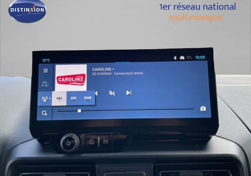 Écran tactile central du tableau de bord du Citroën Berlingo blanc glacier, affichant une radio FM en intérieur.