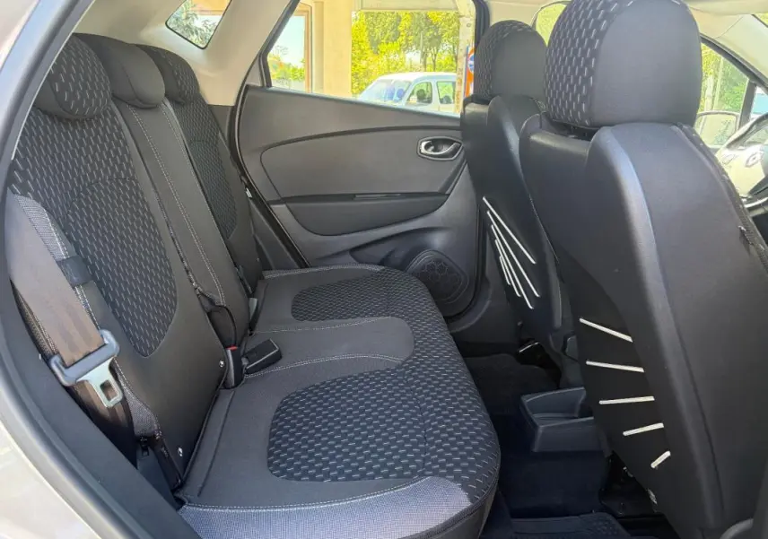 Vue intérieure côté gauche sur la banquette arrière noire du Renault Captur gris avec appuie-têtes et ceinture de sécurité visible.