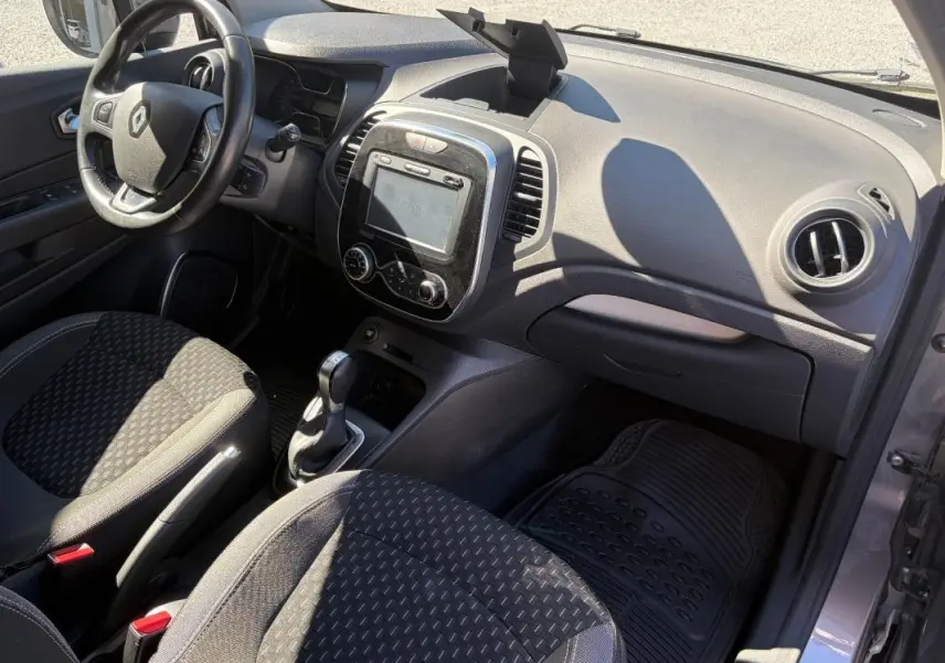 Vue intérieure côté conducteur du Renault Captur gris 2017, avec tableau de bord, écran GPS et volant multifonctions.