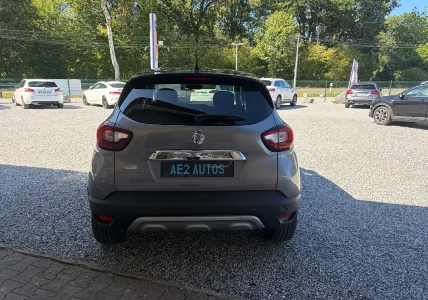 Vue arrière d'un Renault Captur gris 2017 avec jantes alliage et toit noir, stationné sur un sol gravillonné.